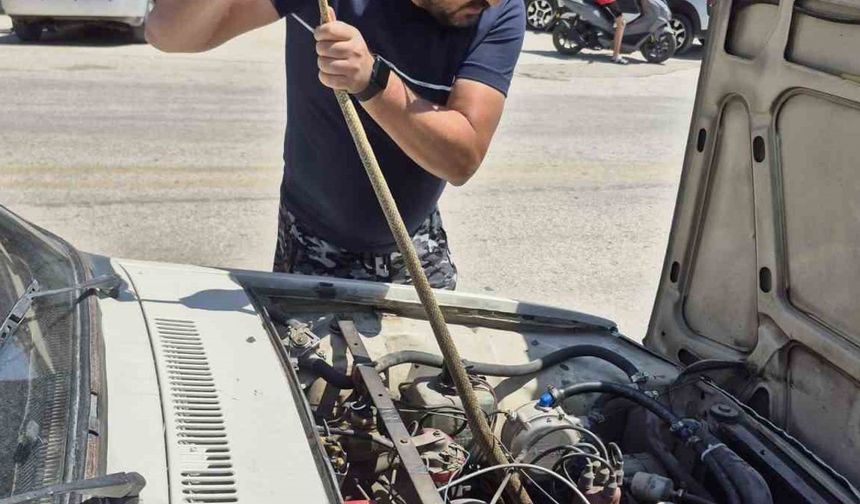 Aracın motoruna giren yılanı elindeki sopayla çıkardı